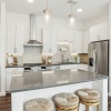 View of kitchen island with barstool seating, white cabinetry, quartz countertops, and stainless steel appliances