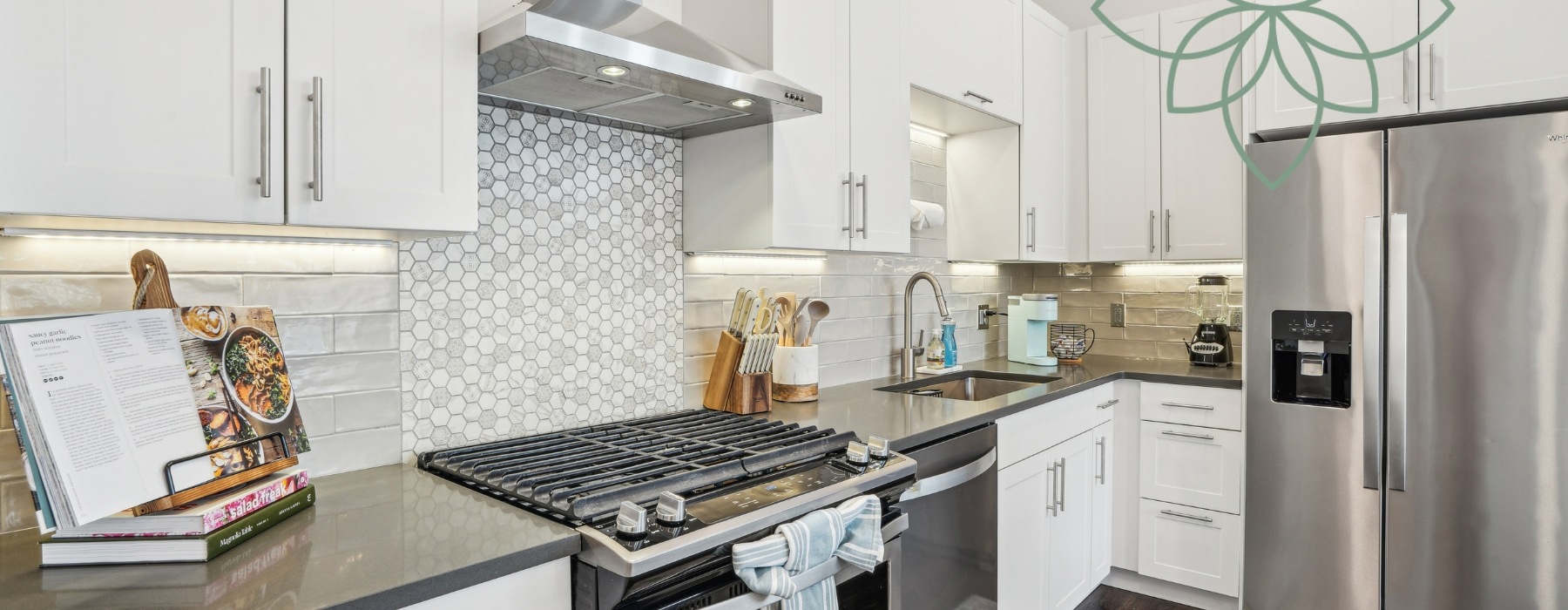 close up on kitchen finishes including gas range, stainless steel appliances, artisan tile backsplash, white cabinetry and quartz countertop