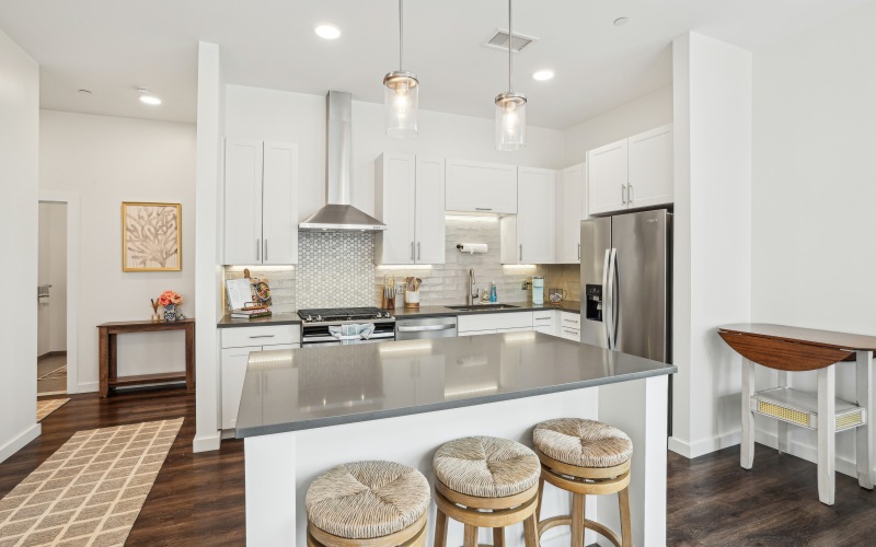 Kitchen with barstool seating, kitchen island, stainless steel appliances, and white cabinetry